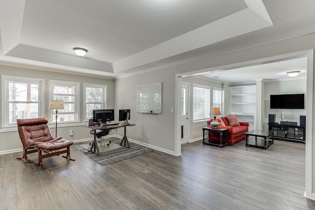 office area with a raised ceiling, built in shelves, and hardwood / wood-style floors