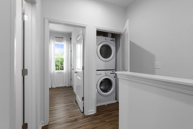 clothes washing area featuring stacked washer / dryer and dark hardwood / wood-style flooring