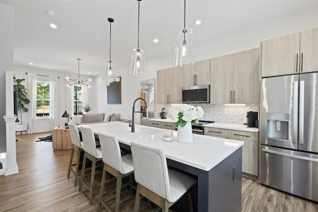 kitchen with a breakfast bar area, an island with sink, appliances with stainless steel finishes, and sink