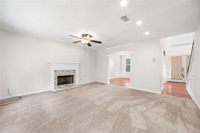 1486 Rogers Crossing Dr, Lithonia, GA 30058 - unfurnished living room with light carpet, a ceiling fan, arched walkways, a fireplace with raised hearth, and recessed lighting