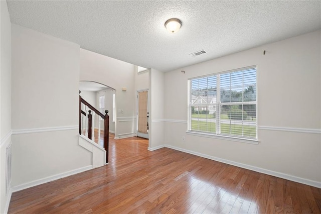 1486 Rogers Crossing Dr, Lithonia, GA 30058 - unfurnished room with arched walkways, wood finished floors, a textured ceiling, stairway, and baseboards