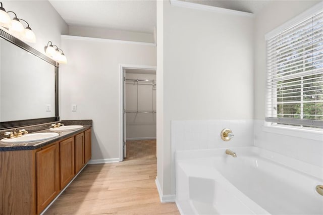 1486 Rogers Crossing Dr, Lithonia, GA 30058 - bathroom with double vanity, a garden tub, wood finished floors, a walk in closet, and baseboards