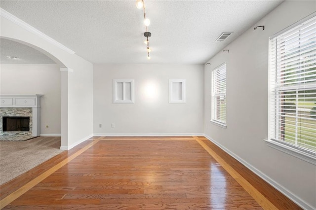 1486 Rogers Crossing Dr, Lithonia, GA 30058 - unfurnished living room featuring arched walkways, light wood-style floors, a textured ceiling, track lighting, and baseboards