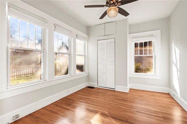 unfurnished bedroom featuring ceiling fan, light wood-type flooring, multiple windows, and a closet