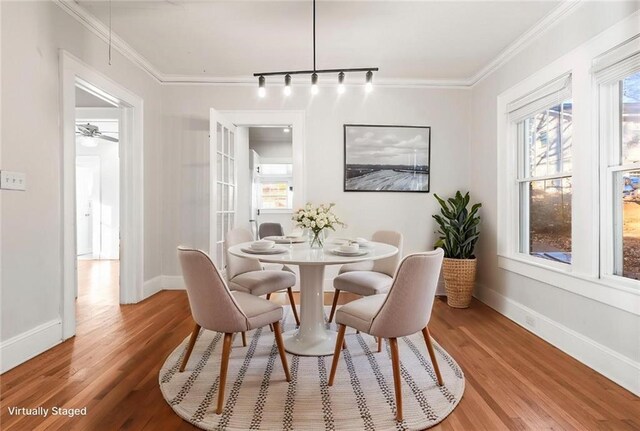 dining room featuring hardwood / wood-style floors, rail lighting, and ornamental molding