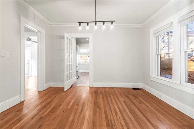 unfurnished dining area with a healthy amount of sunlight, track lighting, light hardwood / wood-style flooring, and ornamental molding