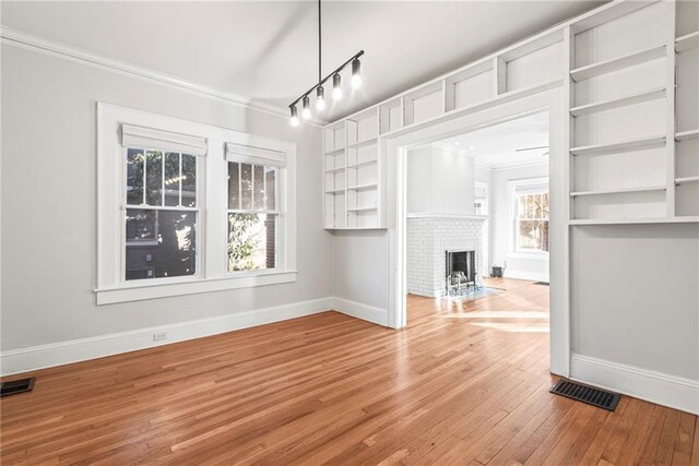 unfurnished living room with crown molding, a fireplace, and light wood-type flooring