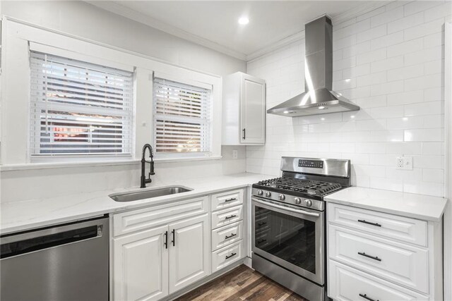 kitchen featuring sink, stainless steel appliances, white cabinetry, and wall chimney range hood