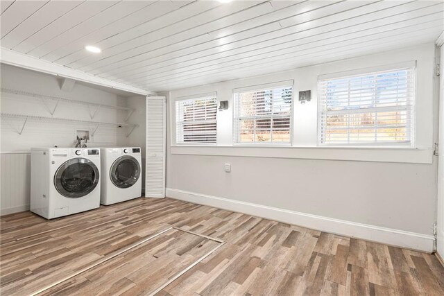 clothes washing area with washer and dryer, wood-type flooring, and wood ceiling