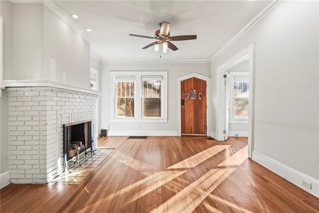 unfurnished living room with ceiling fan, wood-type flooring, crown molding, and a brick fireplace