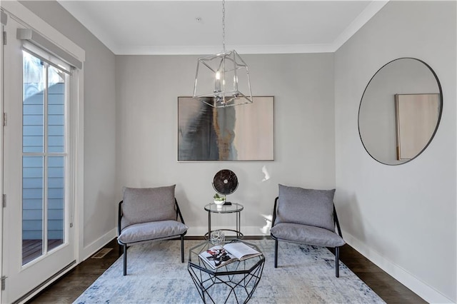 sitting room with ornamental molding, a chandelier, and dark hardwood / wood-style flooring