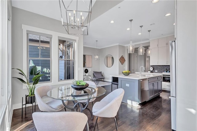 dining area with sink, dark hardwood / wood-style floors, and a chandelier