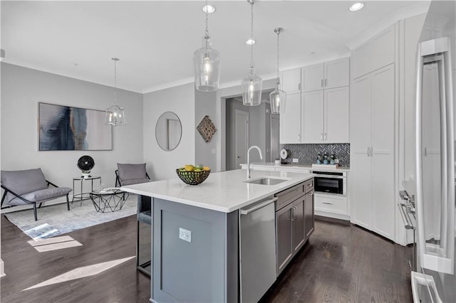 kitchen with sink, decorative light fixtures, a center island with sink, dark hardwood / wood-style floors, and stainless steel appliances