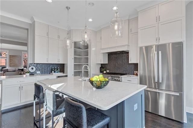 kitchen featuring hanging light fixtures, a center island with sink, white cabinets, and stainless steel refrigerator