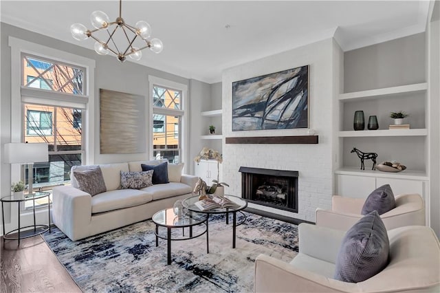 living room featuring built in shelves, a fireplace, a chandelier, and hardwood / wood-style floors