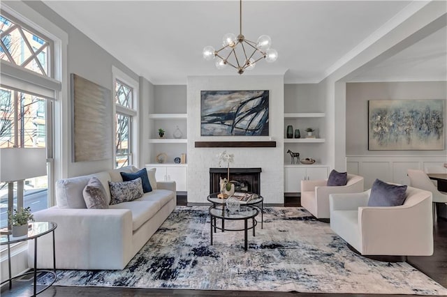 living room featuring a brick fireplace, dark wood-type flooring, built in features, and a chandelier