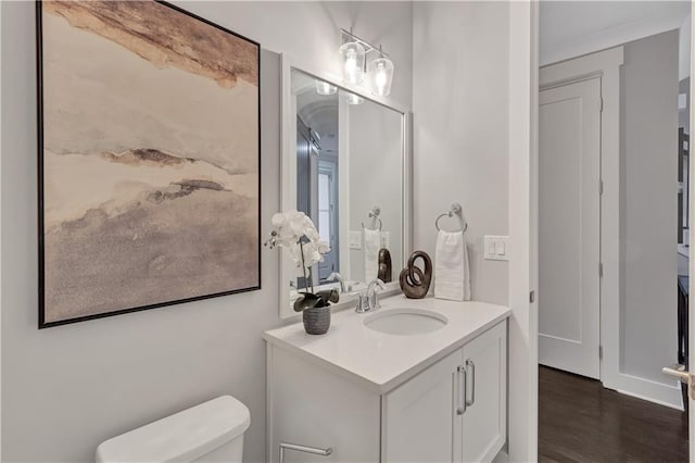 bathroom featuring vanity, wood-type flooring, and toilet