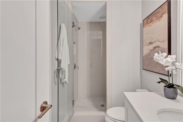 bathroom featuring vanity, a shower with shower door, and toilet