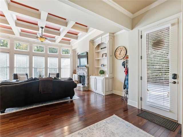 foyer entrance with dark wood-type flooring, beam ceiling, coffered ceiling, a fireplace, and ornamental molding