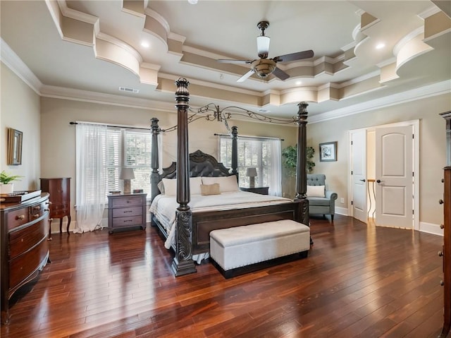 bedroom featuring dark wood-type flooring, ceiling fan, ornamental molding, and a tray ceiling