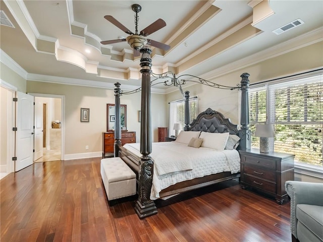 bedroom featuring ornamental molding, dark hardwood / wood-style floors, and a tray ceiling