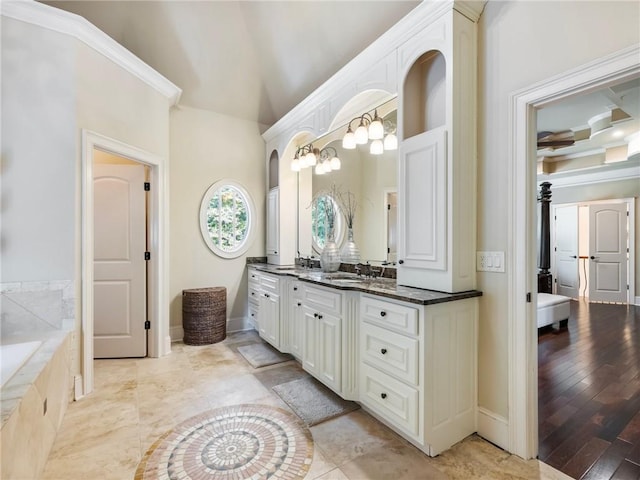 bathroom with ornamental molding, vanity, and tiled tub