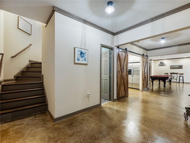 hallway with concrete flooring, crown molding, and a barn door