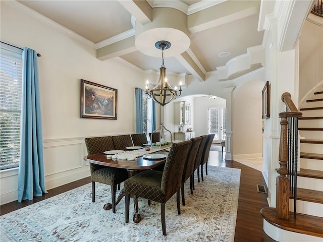 dining space featuring dark wood-type flooring, ornamental molding, a chandelier, and beamed ceiling