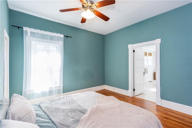 bedroom with ensuite bathroom, wood finished floors, a ceiling fan, and baseboards