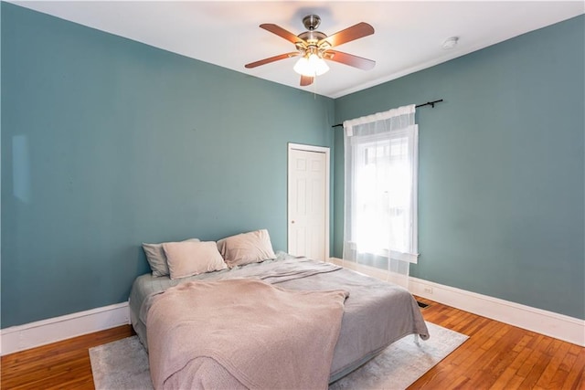 bedroom with ceiling fan, a closet, baseboards, and wood finished floors