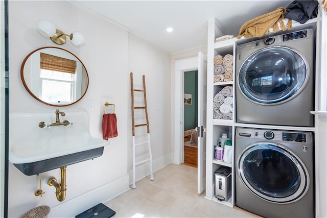 clothes washing area featuring crown molding, recessed lighting, stacked washer / dryer, a sink, and baseboards