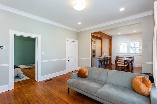 living room featuring dark wood-type flooring, visible vents, crown molding, and baseboards