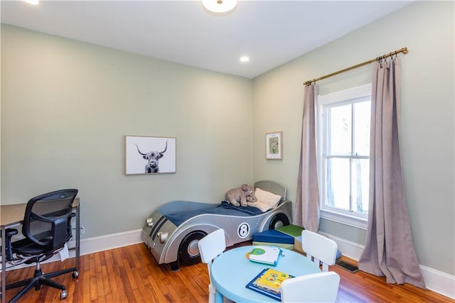 bedroom with multiple windows, wood finished floors, and baseboards