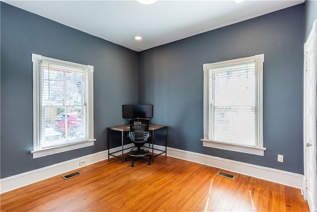 office area featuring baseboards, visible vents, and wood finished floors