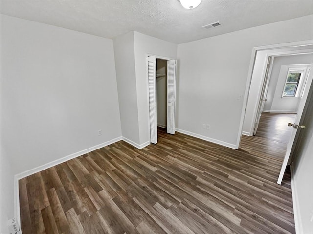 unfurnished bedroom with dark hardwood / wood-style floors, a textured ceiling, and a closet