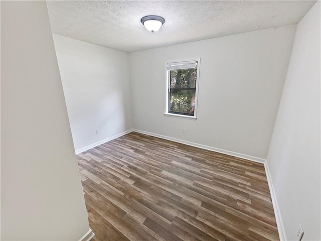 unfurnished room featuring dark wood-type flooring and a textured ceiling