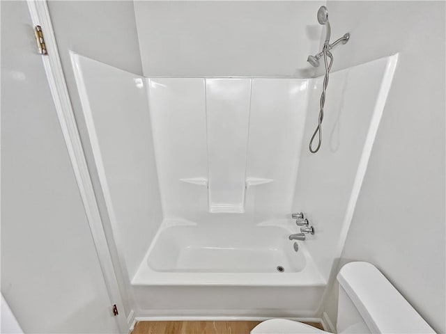 bathroom featuring hardwood / wood-style flooring, shower / tub combination, and toilet