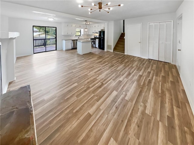 unfurnished living room with a chandelier and light wood-type flooring