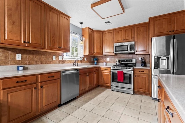 10 Callaway Ct, Hiram, GA 30141 - kitchen with stainless steel appliances, brown cabinetry, light tile patterned floors, decorative light fixtures, and light countertops