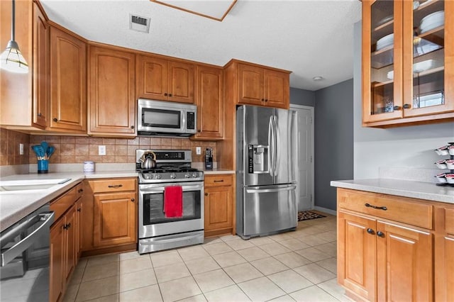 10 Callaway Ct, Hiram, GA 30141 - kitchen with stainless steel appliances, brown cabinets, light countertops, glass insert cabinets, and a textured ceiling