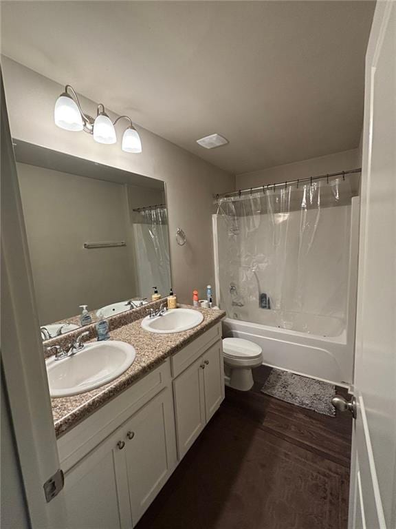 bathroom featuring a sink, shower / bathtub combination with curtain, toilet, and wood finished floors