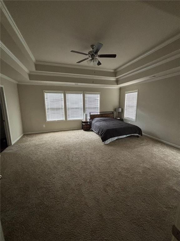 unfurnished bedroom with carpet floors, a ceiling fan, baseboards, ornamental molding, and a raised ceiling