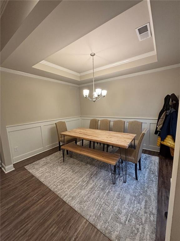 dining space with a chandelier, a tray ceiling, dark wood-style flooring, and visible vents