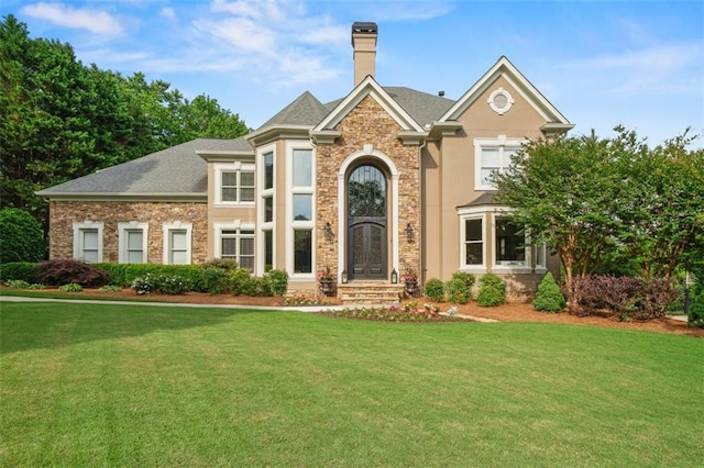 7025 Kettering Ln, Suwanee, GA 30024 - view of front of property with a front yard, stone siding, and a chimney