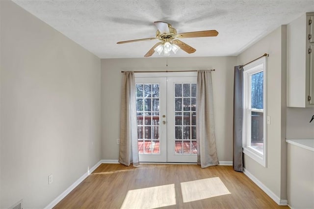 doorway to outside featuring a textured ceiling, french doors, light wood-type flooring, and baseboards