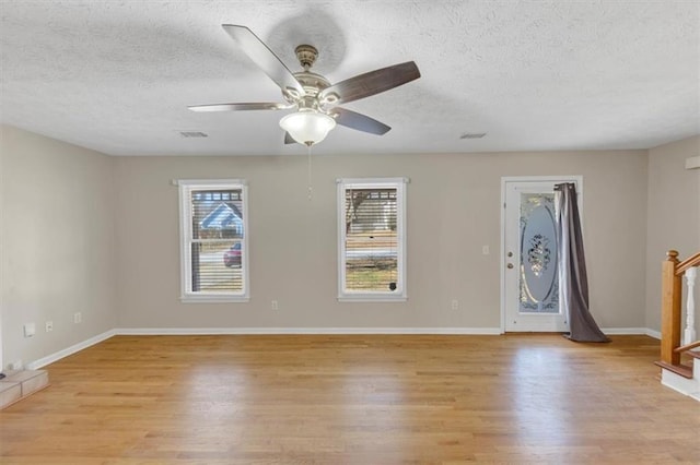 empty room featuring light wood-style flooring, baseboards, and a textured ceiling