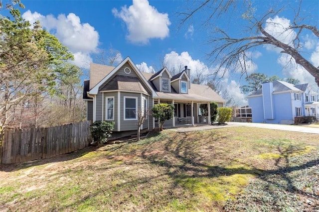 view of front of home with a chimney, fence, and a front yard