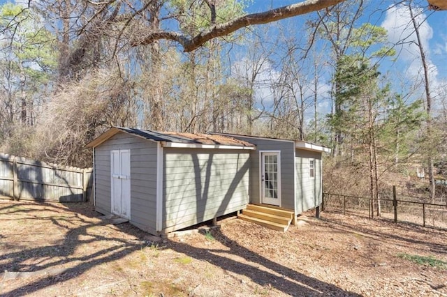 view of outdoor structure with entry steps, an outbuilding, and a fenced backyard