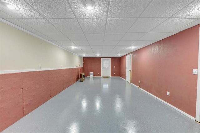 finished basement featuring a drop ceiling and baseboards