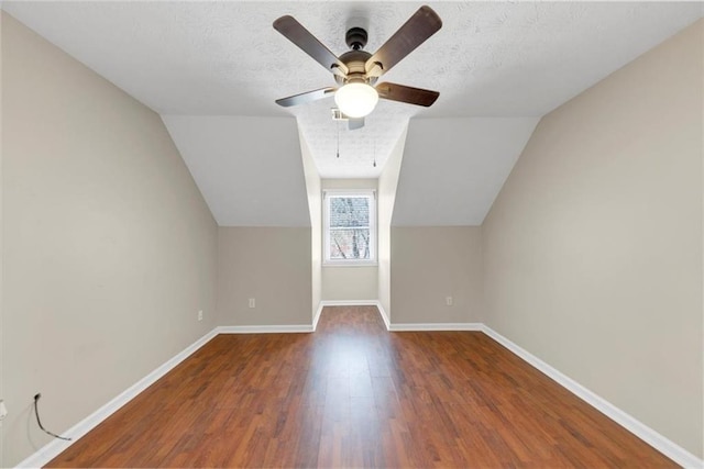 additional living space featuring a textured ceiling, ceiling fan, lofted ceiling, wood finished floors, and baseboards